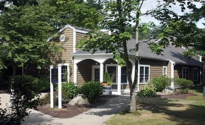 Building with wood siding and white pillars surrounded by trees