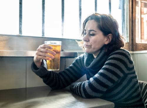 woman looking at beer knowing she needs to make the choice to enter treatment
