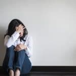 woman sitting on ground against wall suffering from alcohol withdrawal symptoms