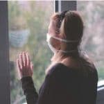 woman looking out at window during pandemic