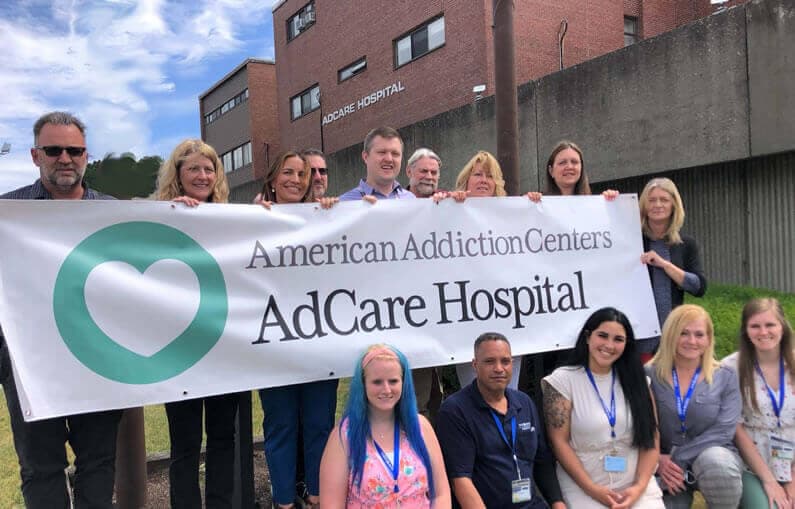 AdCare Hospital staff holding banner of new logo