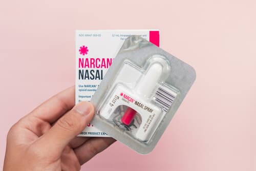 Hand holding a new package of Narcan